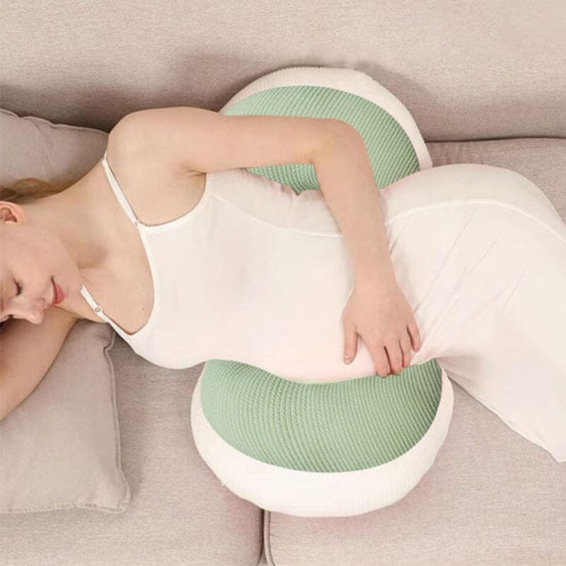 Femme enceinte dormant confortablement sur le côté avec coussin de grossesse rose soutenant ventre et dos pour un sommeil optimal