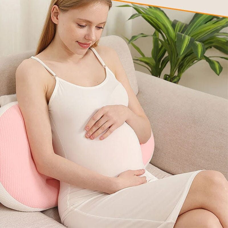 Future maman se relaxant allongée sur canapé avec coussin de grossesse vert sauge offrant soutien complet du corps