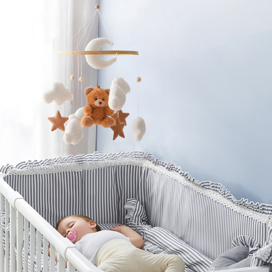 Mobile bebe au dessus berceau avec bebe qui dort paisiblement, nounours marron nuages et croissant lune