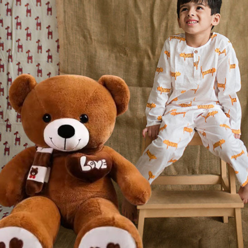 Ours en peluche brun avec écharpe et enfant en pyjama dans chambre
