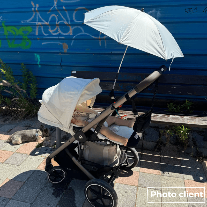Bébé en poussette protégé par parapluie pare-soleil blanc lors d'une sortie extérieure, protection UV efficace