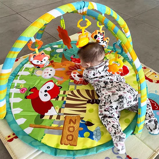 tapis d'éveil avec un bébé couché sur le ventre sur le tapis